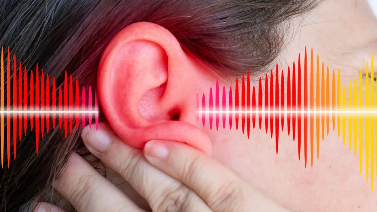 A person holding a small device with two clips on their ear