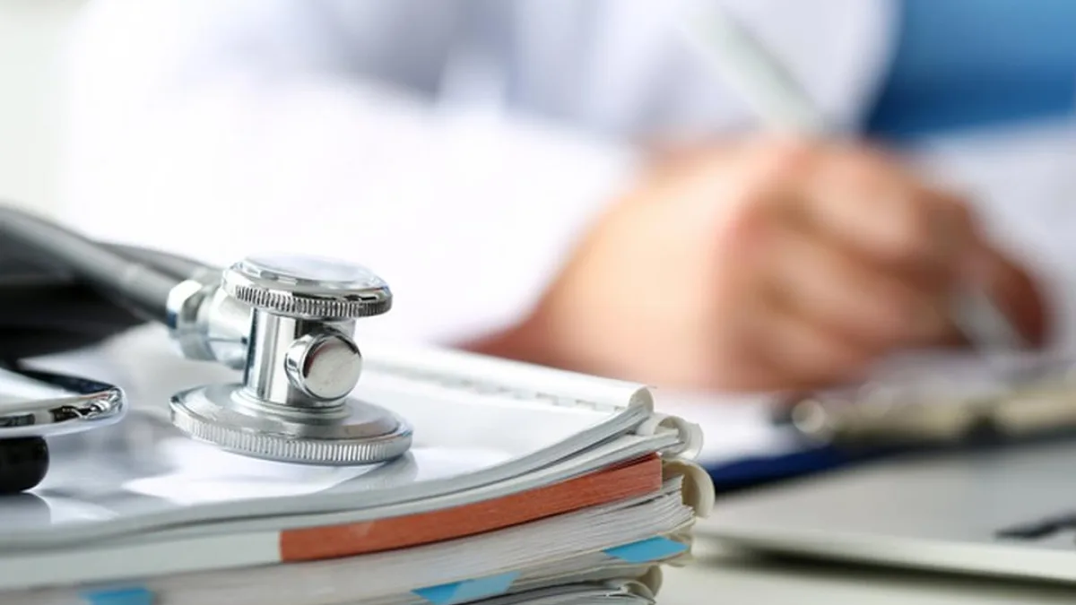 Medical forms on a clipboard with a stethoscope in the background
